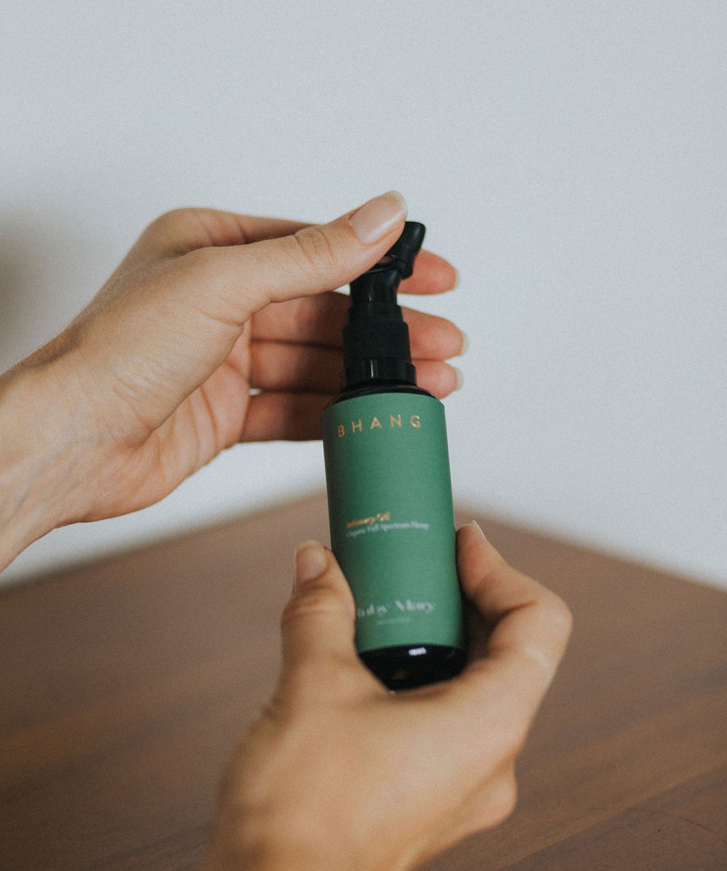 


Hand holding a green spray bottle with a white label on a wooden surface.