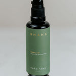 Green bottle with black cap on a reflective surface