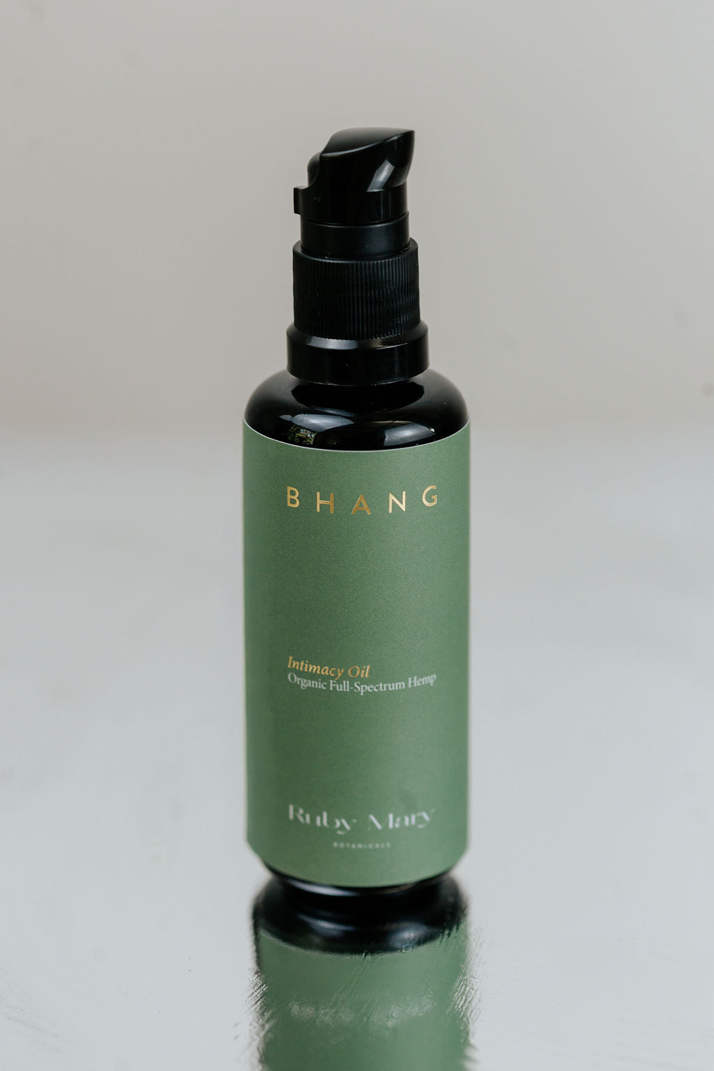 Green bottle with black cap on a reflective surface